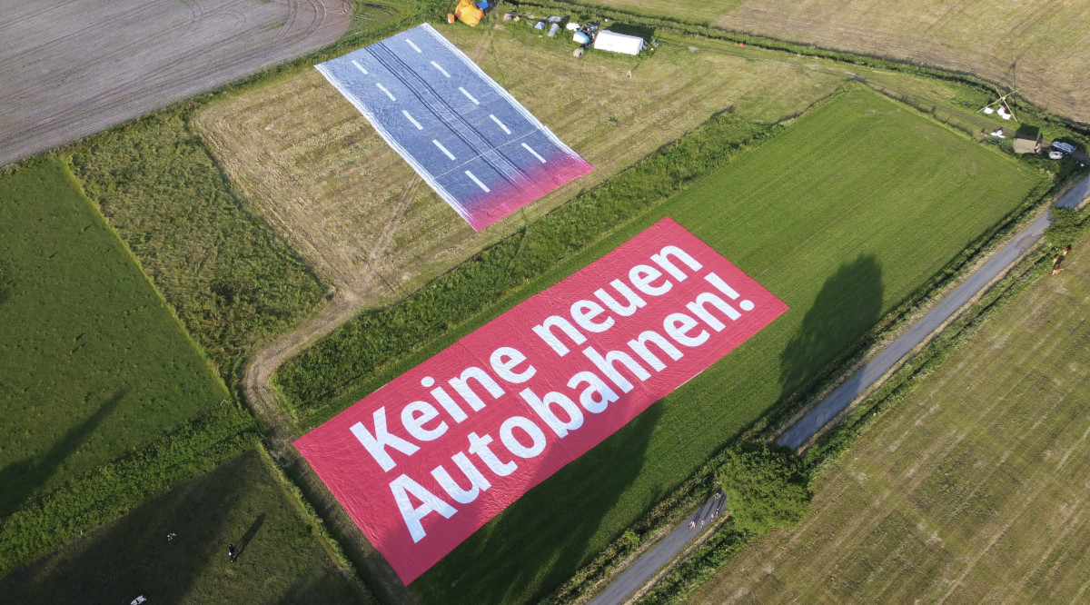 Luftbild der Mahnwache und einem Riesenbanner mit dem Schriftzug 'Keine neuen Autobahnen!'.